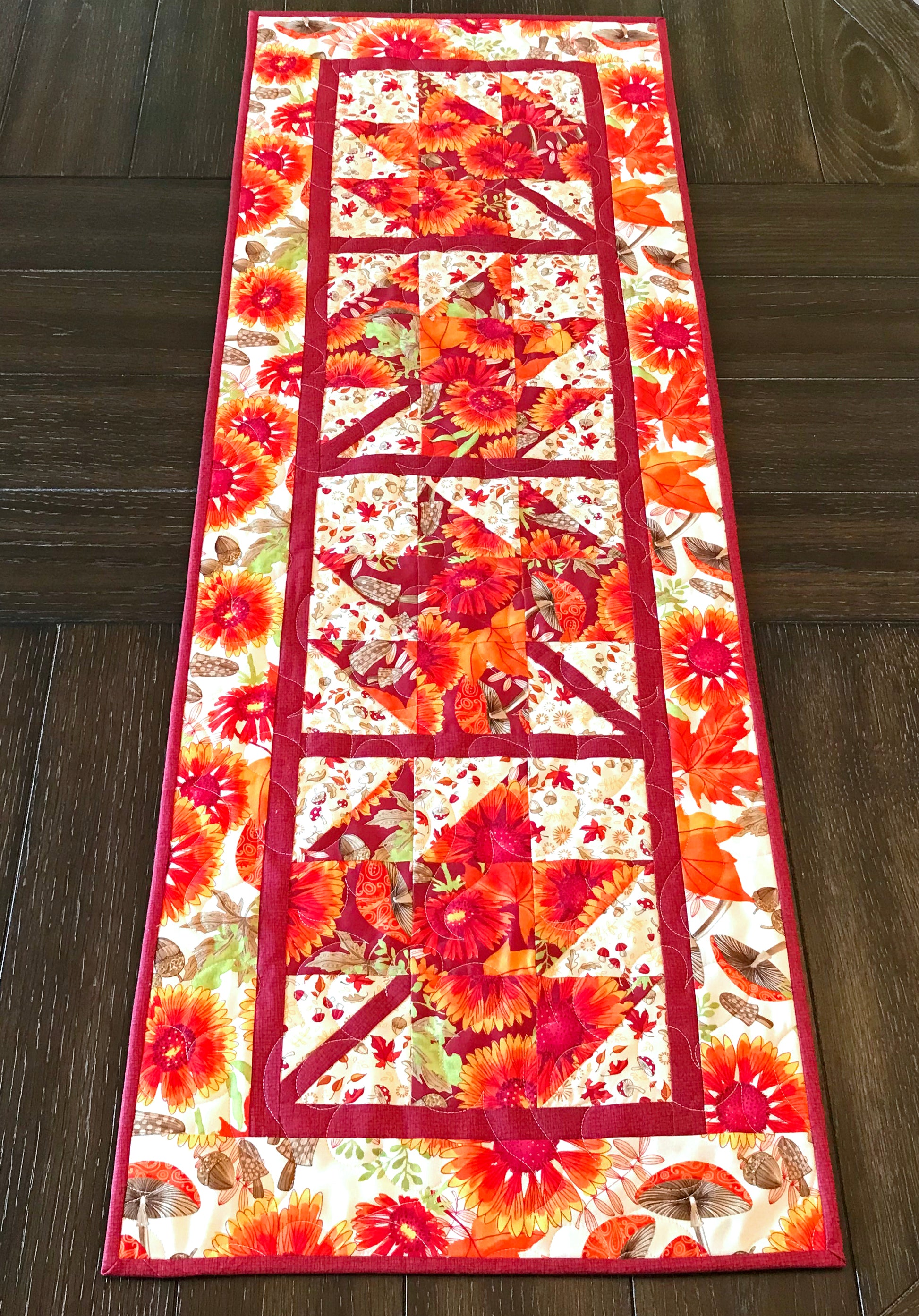 Fall Leaves table runner pattern featuring 4 maple leaf blocks surrounded by sashing and a matching border.