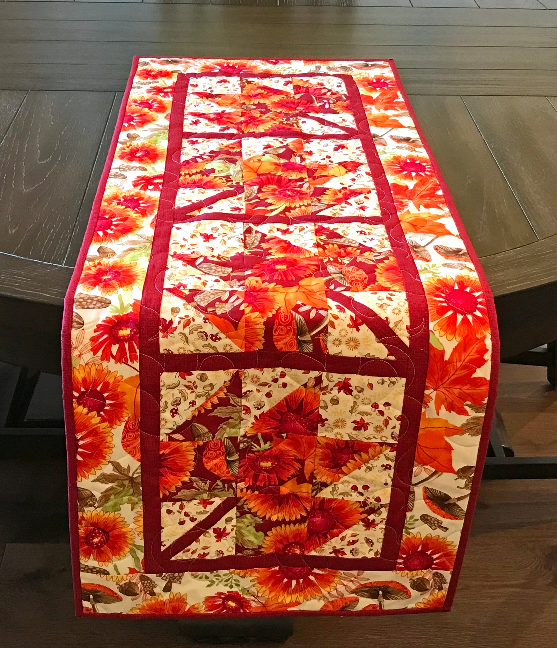 Fall Leaves table runner pattern featuring 4 maple leaf blocks surrounded by sashing and a matching border.