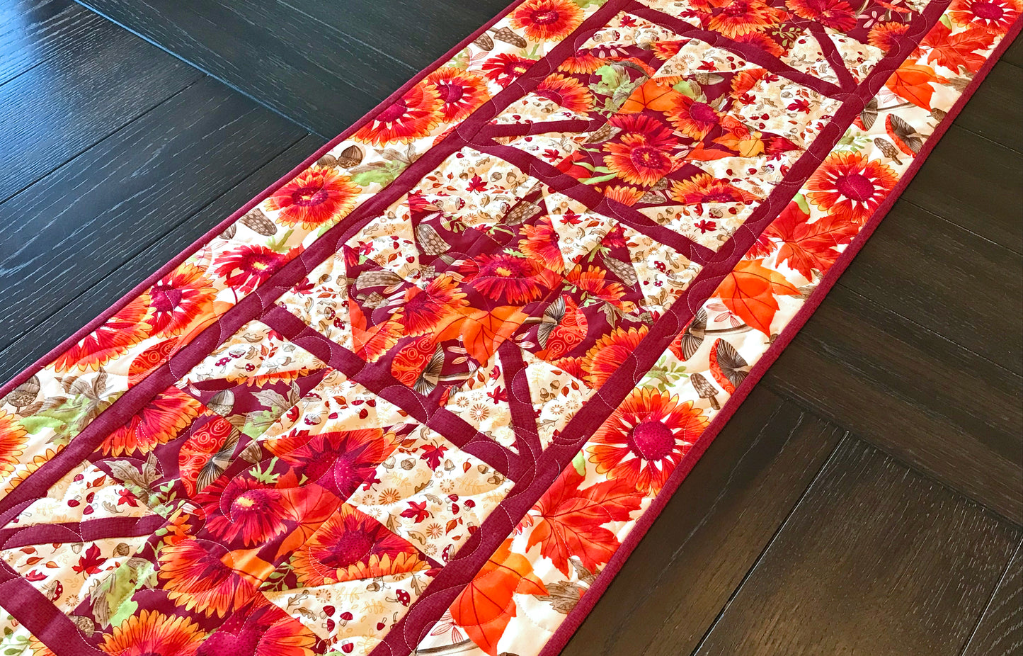 Fall Leaves table runner pattern featuring 4 maple leaf blocks surrounded by sashing and a matching border.