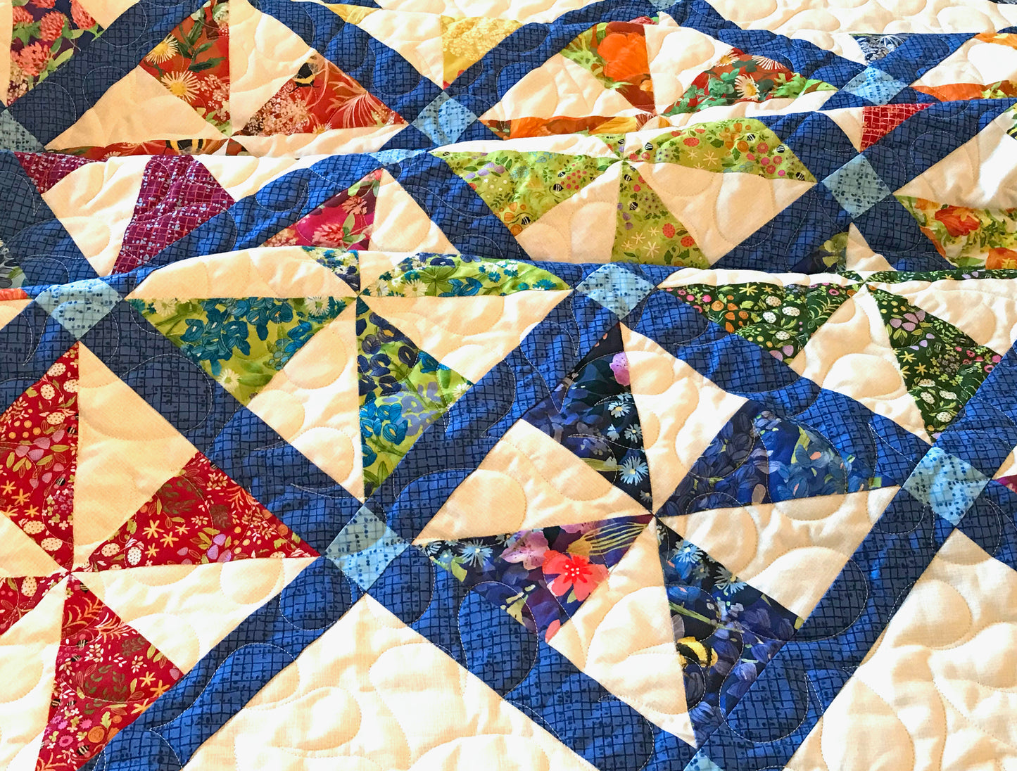 Close up of quilting on Pinwheel Parade quilt pattern featuring pinwheel blocks set on-point with sashing between the blocks and a floral border.