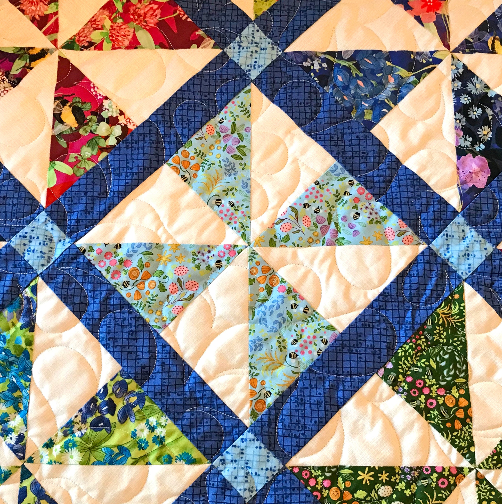 Close up of quilting on Pinwheel Parade quilt pattern featuring pinwheel blocks set on-point with sashing between the blocks and a floral border.