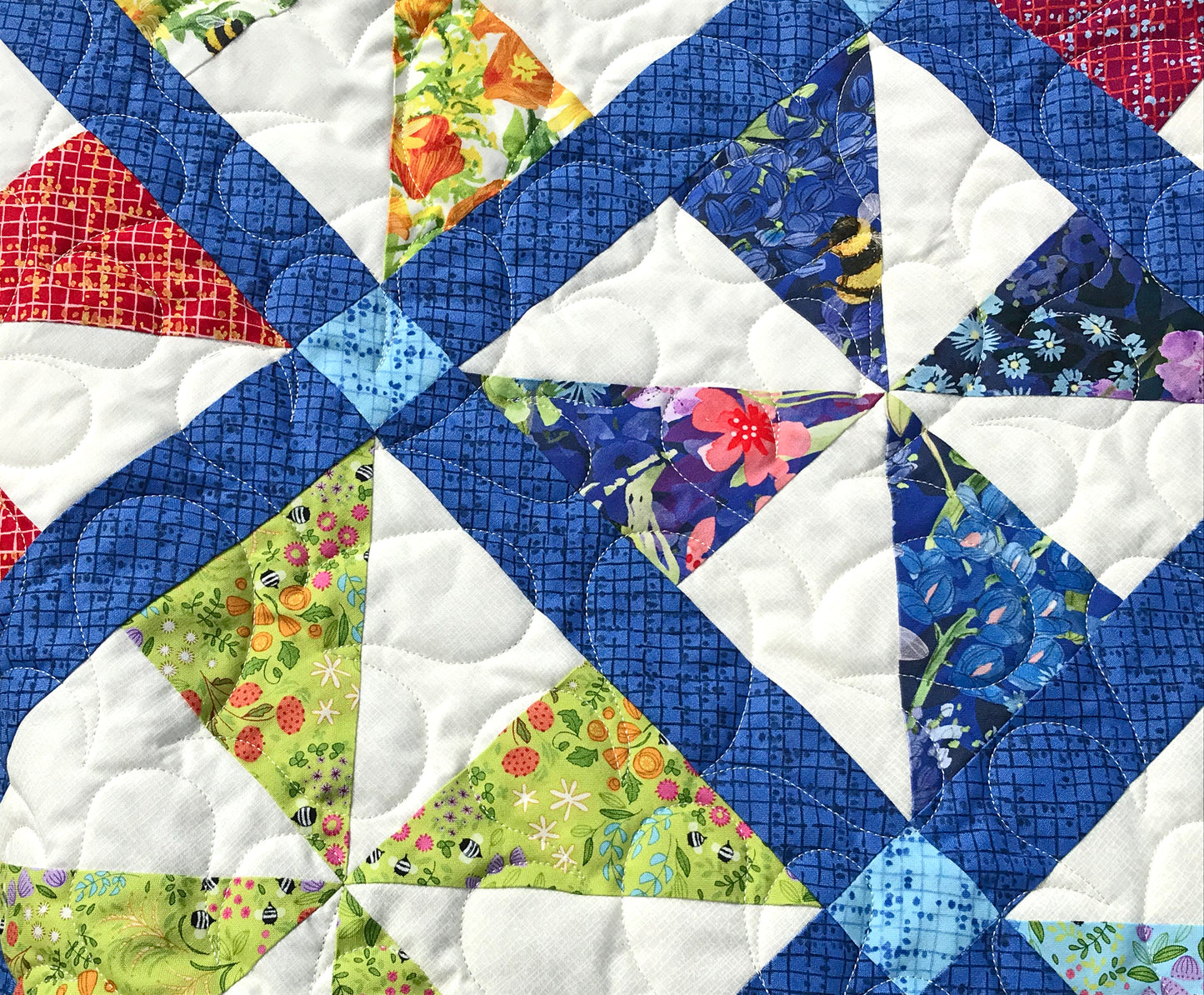 Close up of quilting on Pinwheel Parade quilt pattern featuring pinwheel blocks set on-point with sashing between the blocks and a floral border.