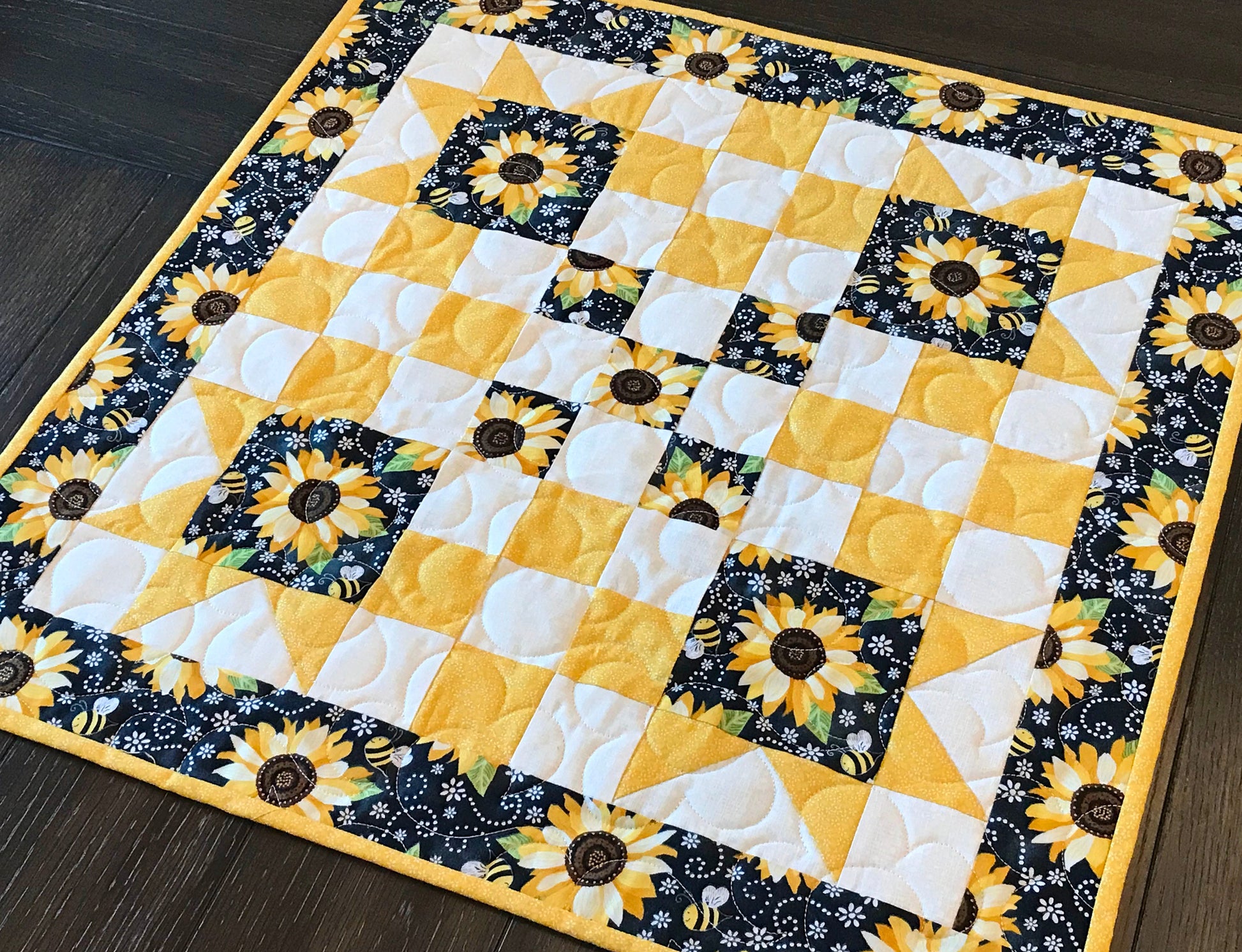 table topper shown on a table for pattern for a table runner or table topper that has sawtooth star corner units with nine patch blocks in between.