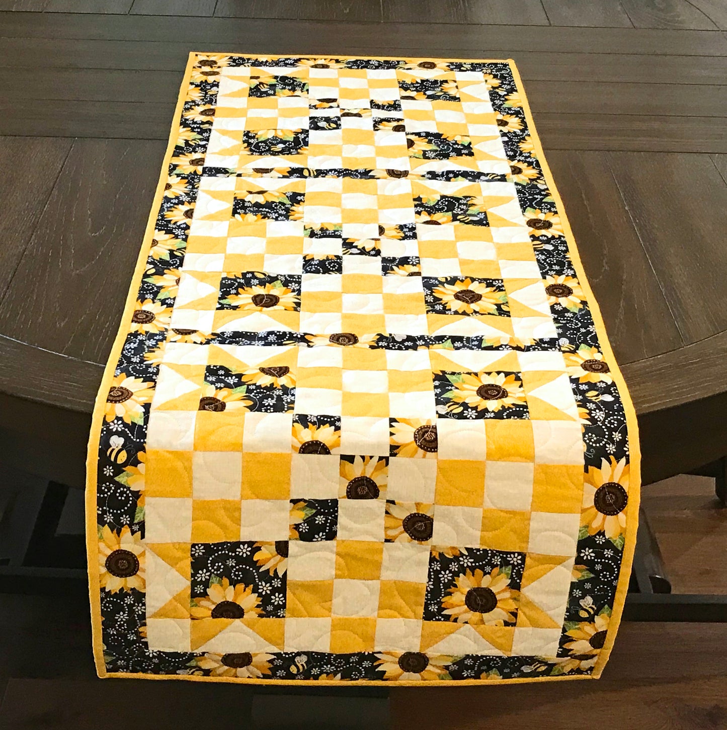 table runner hanging off a table for pattern for a table runner or table topper that has sawtooth star corner units with nine patch blocks in between.