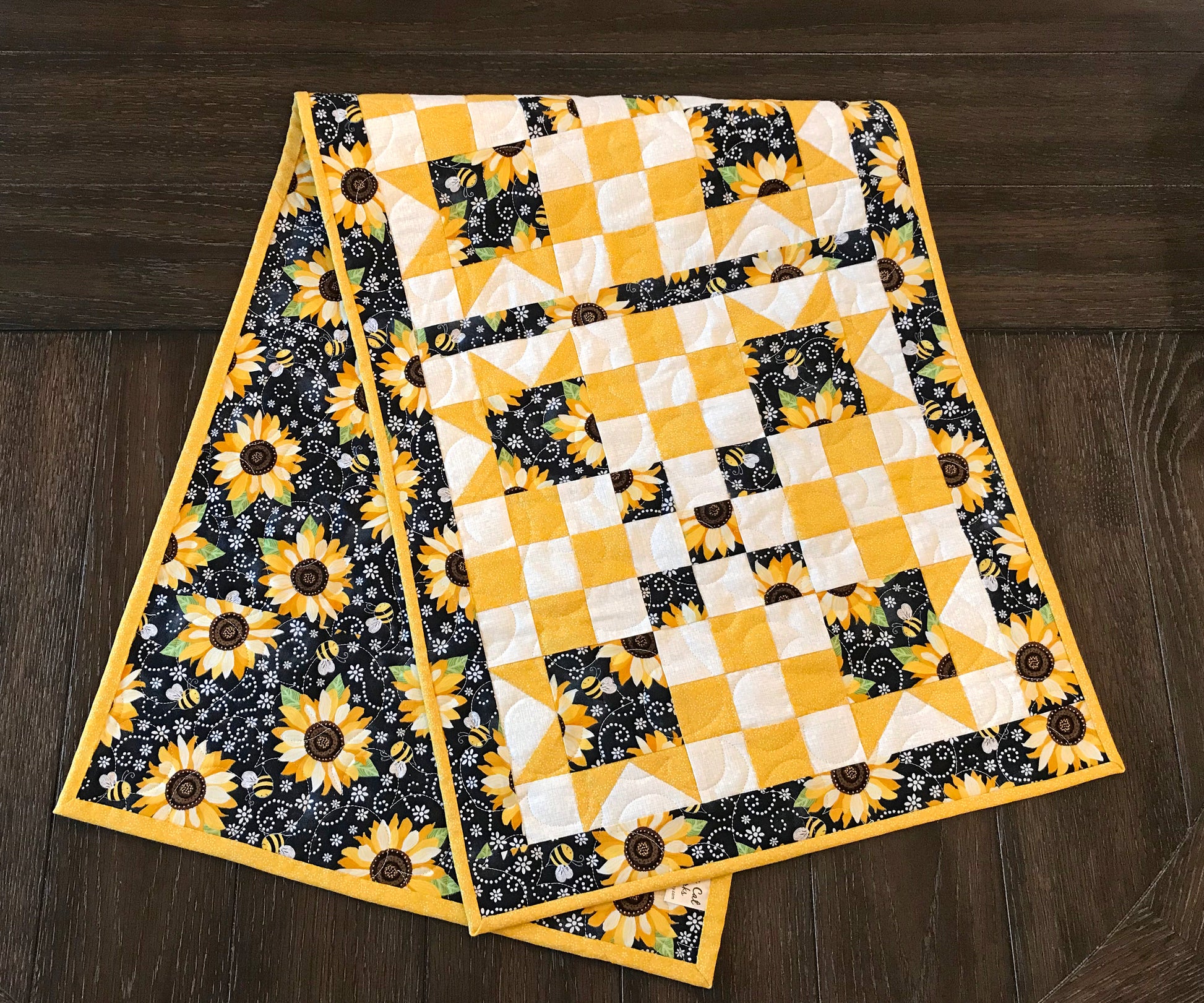 folded table runner on a table for pattern for a table runner or table topper that has sawtooth star corner units with nine patch blocks in between.