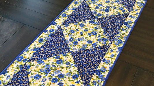 Blue and yellow floral table runner with a center diamond pattern displayed on a table