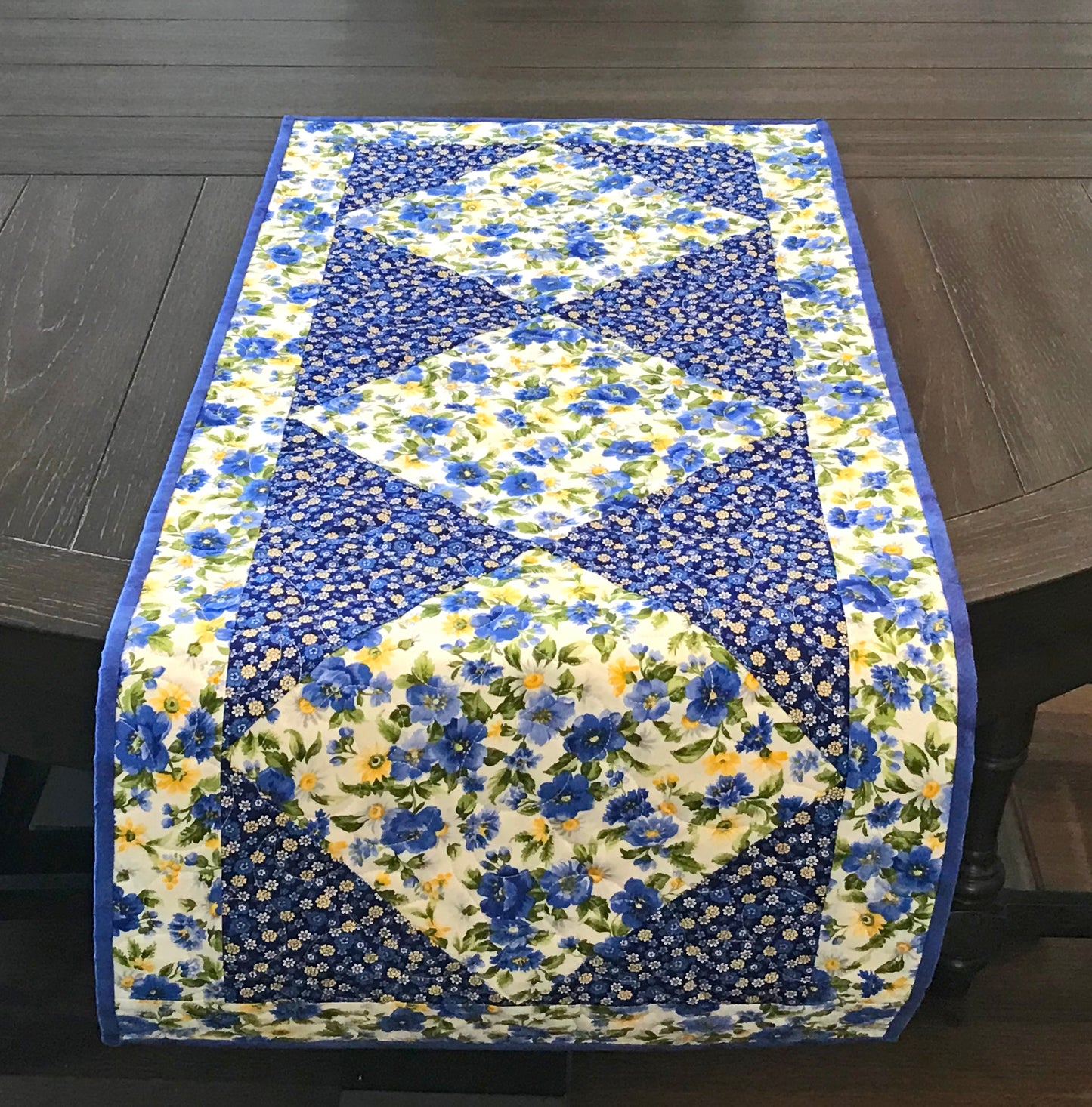 Blue and yellow floral table runner with a center diamond pattern displayed on a table