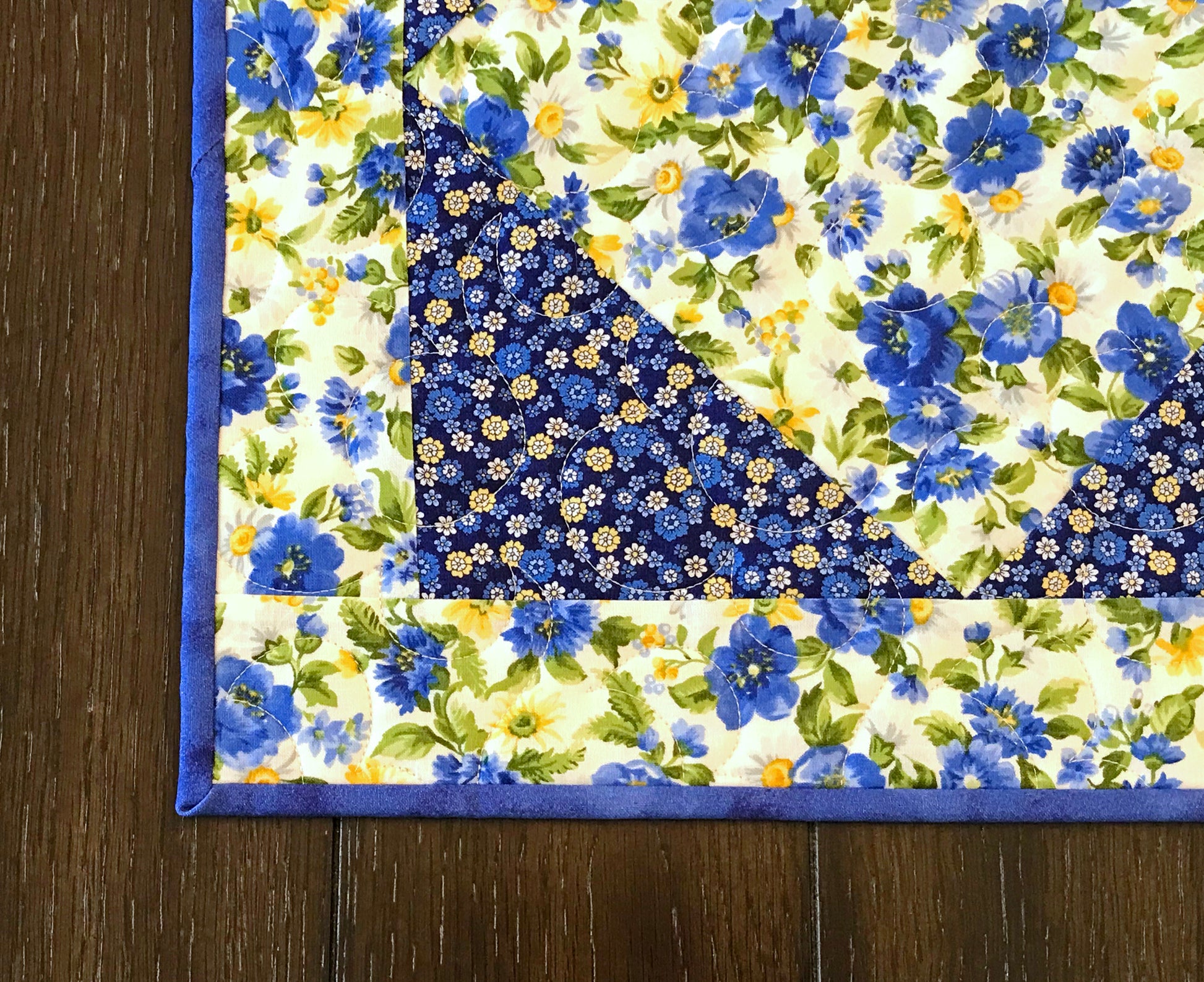 lose up of corner on Blue and yellow floral table runner with a center diamond pattern displayed on a table