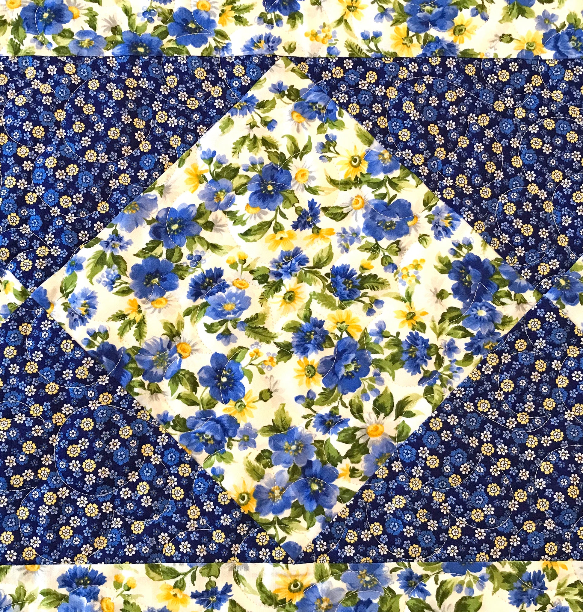 Close up of Blue and yellow floral table runner with a center diamond pattern displayed on a table