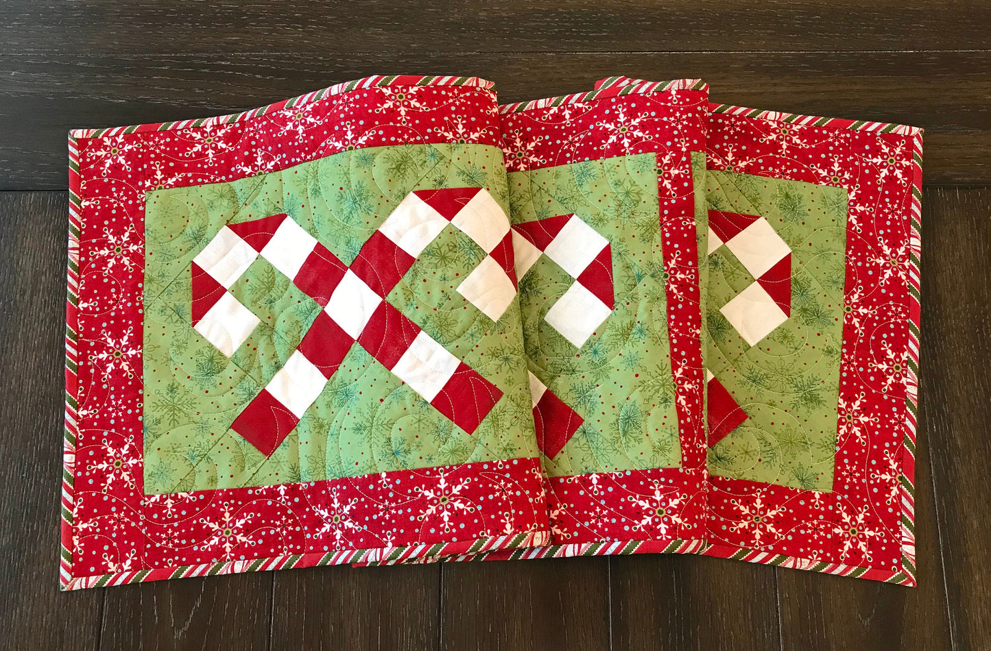 Digital pattern for a quilted Christmas table runner that has candy canes in three sections surrounded by a border.