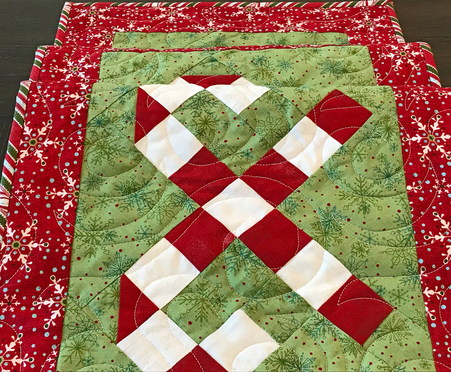 Digital pattern for a quilted Christmas table runner that has candy canes in three sections surrounded by a border.