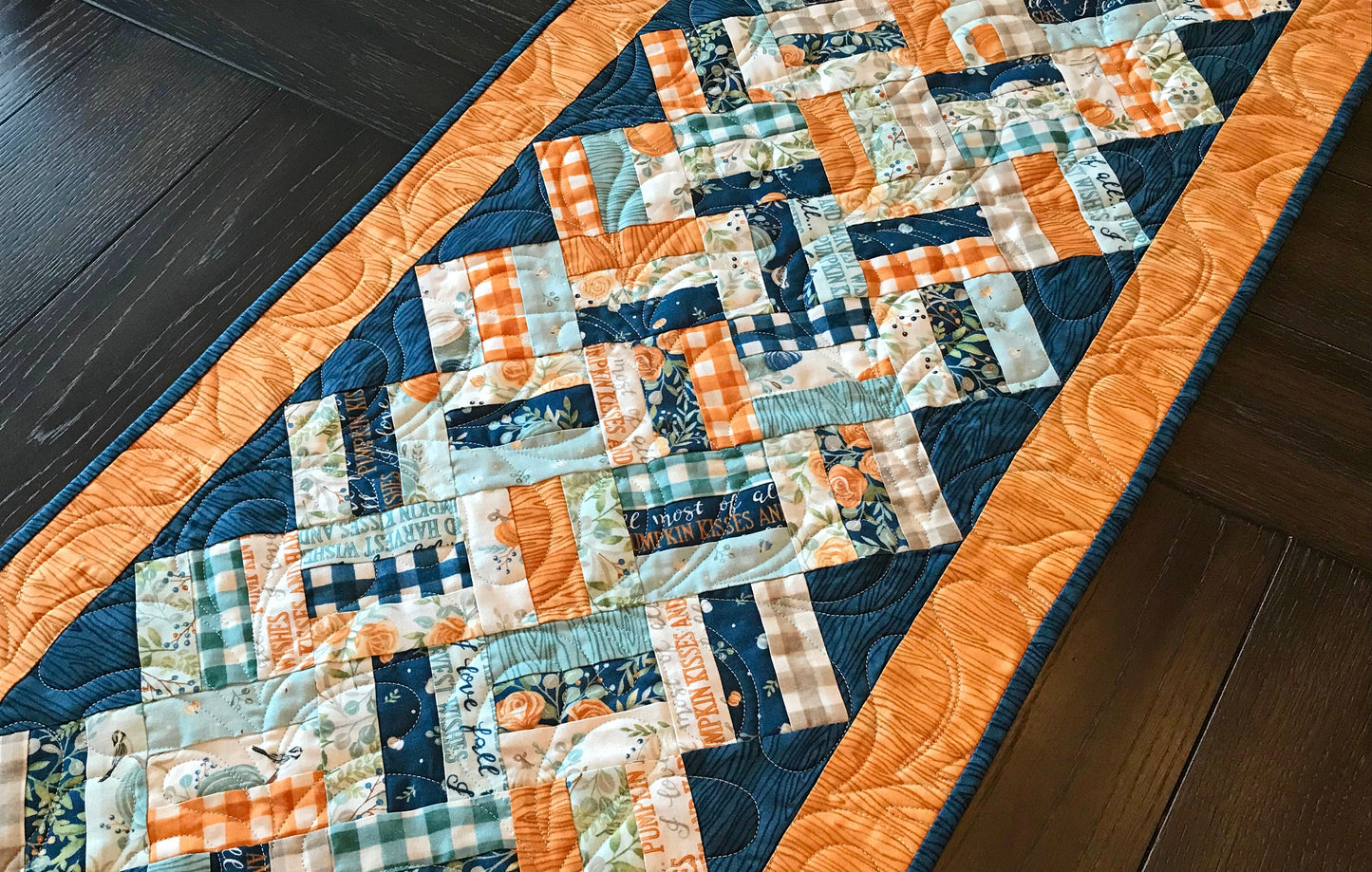 Braided Squares table runner and topper pattern. Sample runner and topper shown with a fall color scheme of dark blue, aqua, cream and orange.