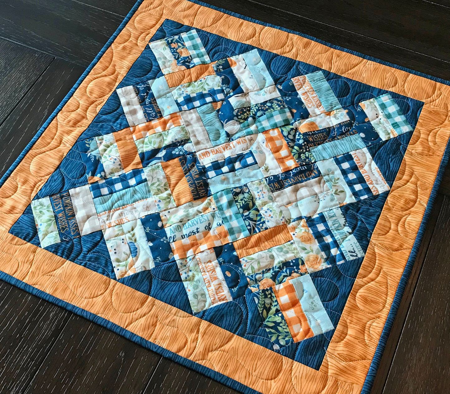 Braided Squares table runner and topper pattern. Sample runner and topper shown with a fall color scheme of dark blue, aqua, cream and orange.